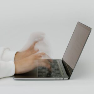Hands rapidly typing on a laptop, illustrating speed and technology in a digital work environment.