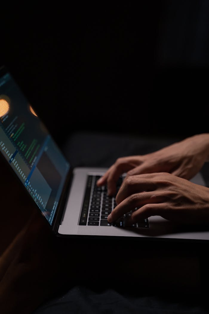 about-bg Hands typing code on a laptop keyboard in a dark room, capturing the essence of late-night programming.