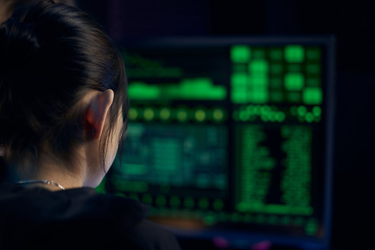 get-in-touch A woman focuses on data displayed on a computer screen in a dark room.
