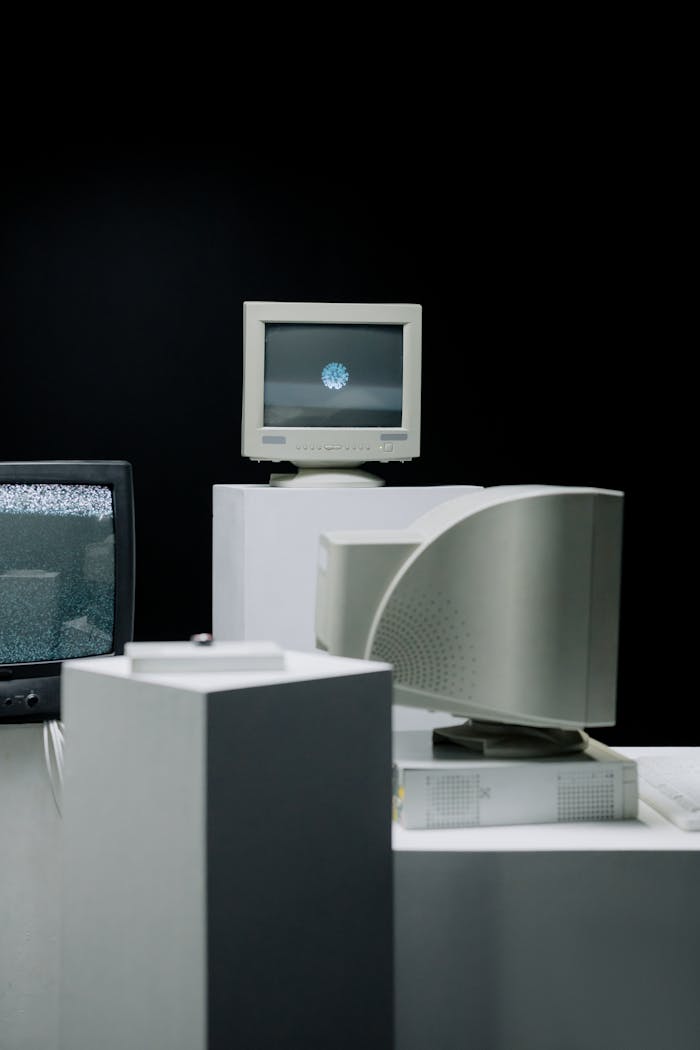 who-we-are Vintage computer monitors arranged in a minimalist setup with a dark background, showcasing technology evolution.